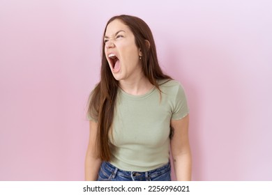 Beautiful brunette woman standing over pink background angry and mad screaming frustrated and furious, shouting with anger. rage and aggressive concept.  - Shutterstock ID 2256996021