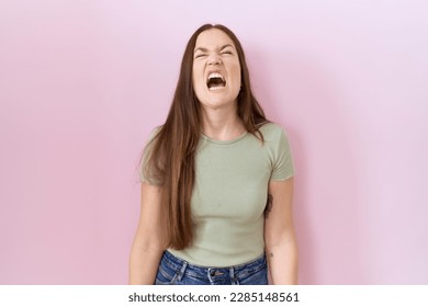 Beautiful brunette woman standing over pink background angry and mad screaming frustrated and furious, shouting with anger. rage and aggressive concept.  - Shutterstock ID 2285148561