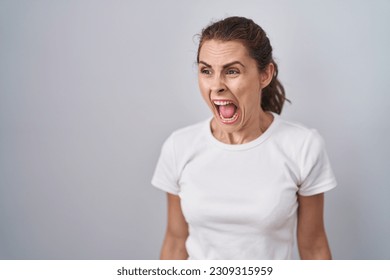 Beautiful brunette woman standing over isolated background angry and mad screaming frustrated and furious, shouting with anger. rage and aggressive concept.  - Shutterstock ID 2309315959