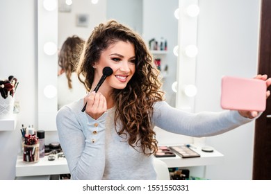 Beautiful Brunette Woman Taking Selfie Photo While Applying Makeup In Front Of Mirror.