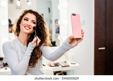 Beautiful Brunette Woman Taking Selfie Photo While Applying Makeup In Front Of Mirror.