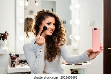 Beautiful Brunette Woman Taking Selfie Photo While Applying Makeup In Front Of Mirror.