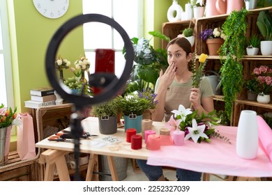 Beautiful brunette woman working at florist shop recording tutorial and smartphone covering mouth and hand  shocked   afraid for mistake  surprised expression 