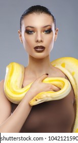 Beautiful brunette women with a albine python. Fashion makeup