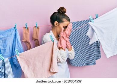 Beautiful Brunette Young Woman Washing Clothes At Clothesline With Sad Expression Covering Face With Hands While Crying. Depression Concept. 