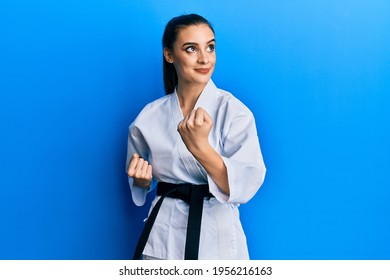 Beautiful Brunette Young Woman Wearing Karate Fighter Uniform With Black Belt Doing Attack Pose Smiling Looking To The Side And Staring Away Thinking. 