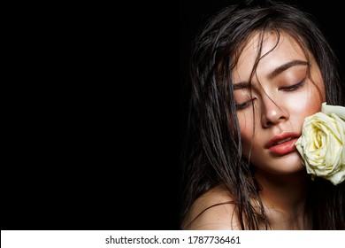 Beautiful Brunette Young Woman With Wet Long Hair And  Natural Glowing Makeup Holding White Rose Flower. Studio Beauty Shot.