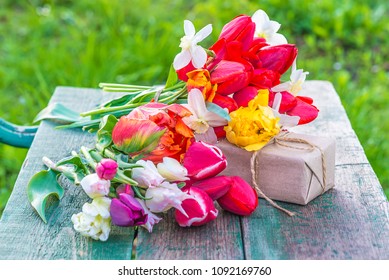 Beautiful bunch of multicolred tulips and hand made gift box on rustic background outdoors