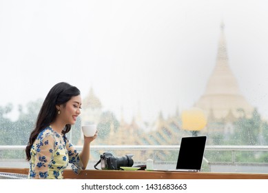 Beautiful Burmese Girl And Drinking Coffee Looking Outside Through A Window In A Rainy Day With The Shwedagon Pagoda In The Background 