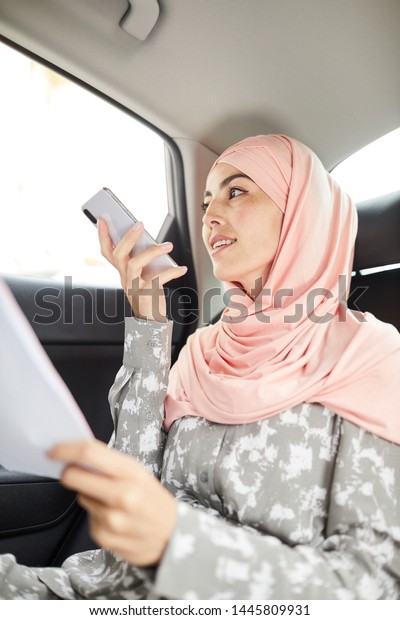 Beautiful business lady in
hijab recording audio message to coworker when riding to work or
meeting
