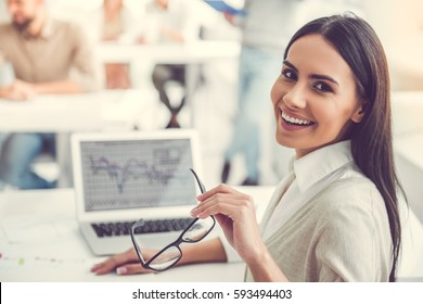 Schöne Geschäftsfrau sieht Kamera und Lächeln während der Arbeit im Büro