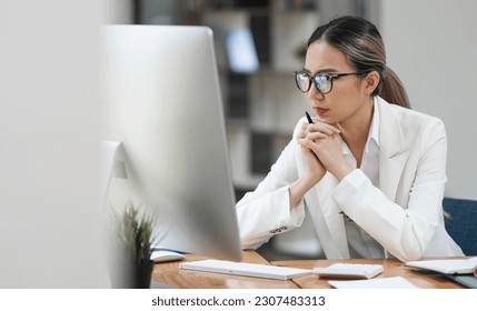 Beautiful business lady looking seriously watching on desktop monitor screen, sitting in modern office. - Powered by Shutterstock