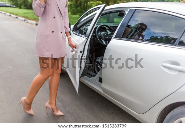 Beautiful business\
lady woman opens and closes car door, summer in city, business\
class car, VIP taxi, pink suit, long tanned legs with high heel\
shoes. Parking in city alarm\
off.