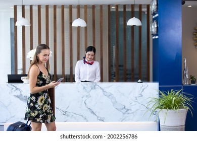 Beautiful business woman carrying a suitcase in a travel trip  at hotel counter customer service