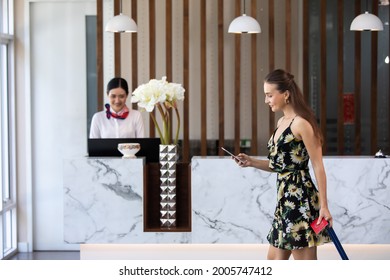 Beautiful business woman carrying a suitcase in a travel trip  at hotel counter customer service