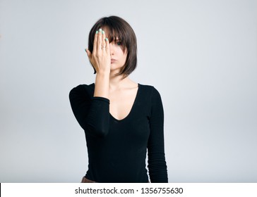 Beautiful Business Woman Closes One Eye With Hand Isolated On Gray Background