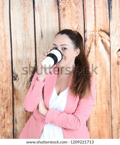 Beautiful business woman drinking a cup of coffee against a wooden background