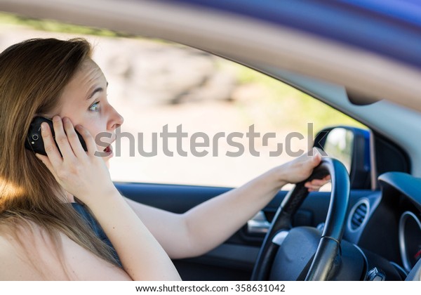 Beautiful business woman driving a car,\
talking on the mobile phone. Careful driving\
concept