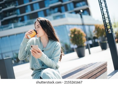 Beautiful Business Woman Enjoying Coffee Break On Free Time Outdoor With Favorite Music In Earphones, Millenial Female Listening Audio Book On Mobile App 