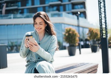 Beautiful Business Woman Enjoying Coffee Break On Free Time Outdoor With Favorite Music In Earphones, Millenial Female Listening Audio Book On Mobile App 