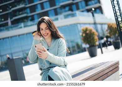 Beautiful Business Woman Enjoying Coffee Break On Free Time Outdoor With Favorite Music In Earphones, Millenial Female Listening Audio Book On Mobile App 