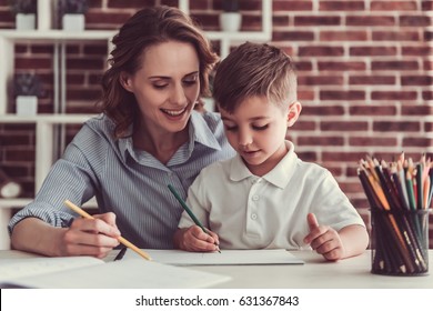 Beautiful business woman   her cute little son are drawing   smiling while sitting in office