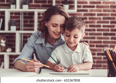 Beautiful business woman and her cute little son are drawing and smiling while sitting in office