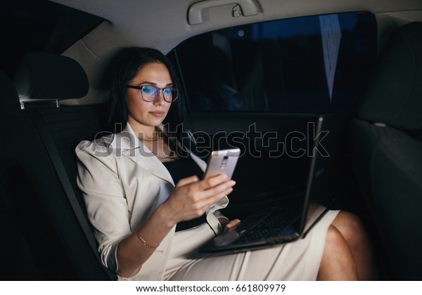 Beautiful\
business woman sitting in back seat of\
car