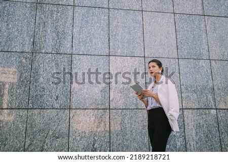 Beautiful business woman standing infront of the wall with her tablet
