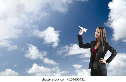 Beautiful Business Woman Throwing A Paper Plane, Against A Beautiful Blue Sky