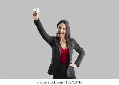 Beautiful Business Woman Throwing A Paper Plane, Over A Gray Background