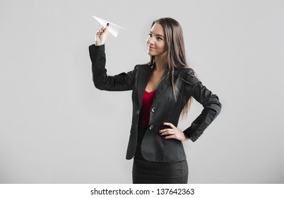 Beautiful Business Woman Throwing A Paper Plane, Over A Gray Background