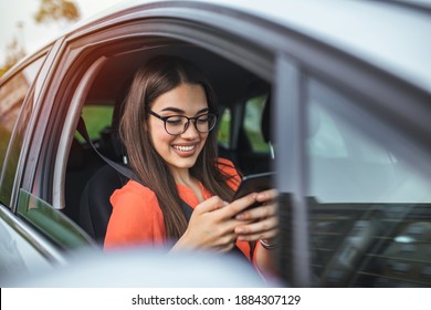 Beautiful business woman is using a smart phone and smiling while sitting on front seat in the car. Portrait of beautiful smiling happy woman in a car. Beautiful business woman in car. - Powered by Shutterstock