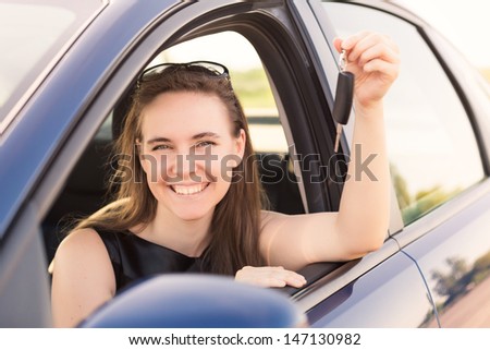 Beautiful businesswoman with carkey in her car