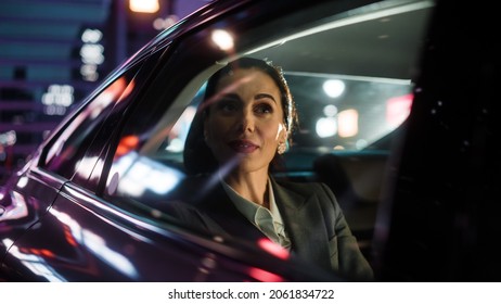 Beautiful Businesswoman is Commuting from Office in a Backseat of Her Luxury Car at Night. Entrepreneur Passenger Traveling in a Transfer Taxi in Urban City Street with Working Neon Signs.