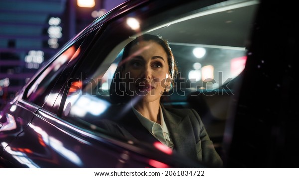 Beautiful\
Businesswoman is Commuting from Office in a Backseat of Her Luxury\
Car at Night. Entrepreneur Passenger Traveling in a Transfer Taxi\
in Urban City Street with Working Neon\
Signs.