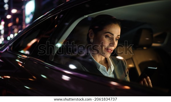 Beautiful\
Businesswoman is Commuting from Office in a Backseat of Her Luxury\
Car at Night. Entrepreneur Using Smartphone while in Transfer Taxi\
in Urban City Street with Working Neon\
Signs.