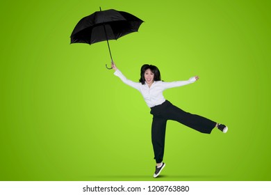 Beautiful businesswoman dancing with an umbrella in the studio with green screen - Powered by Shutterstock