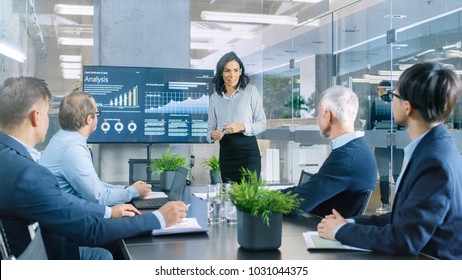 Beautiful Businesswoman Gives Report/ Presentation to Her Business Colleagues in the Conference Room, She Shows Graphics, Pie Charts and Company's Growth on the Wall TV. - Shutterstock ID 1031044375