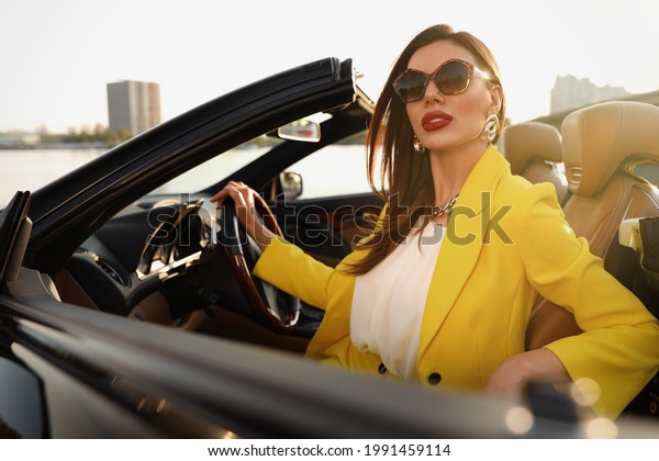 Beautiful businesswoman in luxury convertible\
car outdoors