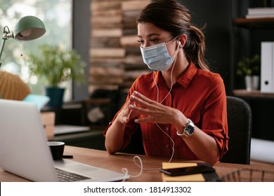 Beautiful businesswoman with medical mask working in office. Young businesswoman working on lap top.	
