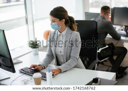 Beautiful businesswoman with medical mask working in office. Covid-19 concept.