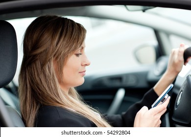 Beautiful businesswoman sending a text while driving to work