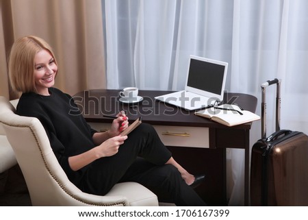 A beautiful businesswoman is sitting at a table in a hotel room. Freelancer at work. Copy space.