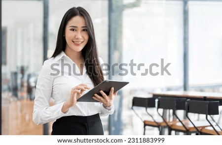 Beautiful businesswoman standing in office with digital tablet