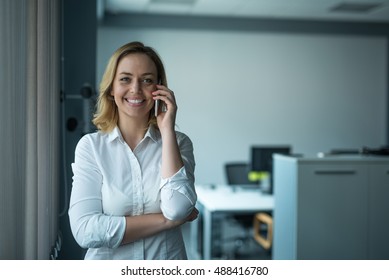 Beautiful businesswoman talking on the phone with clients in an office. - Shutterstock ID 488416780