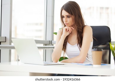 Schöne Geschäftsfrau, die in einem hellen, modernen Büro an einem Laptop arbeitet