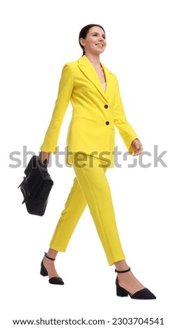 Beautiful businesswoman in yellow suit with briefcase walking on white background, low angle view