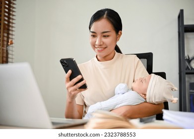 Beautiful busy Asian mother working from home, talking on the phone and holding her baby with her arms  - Powered by Shutterstock