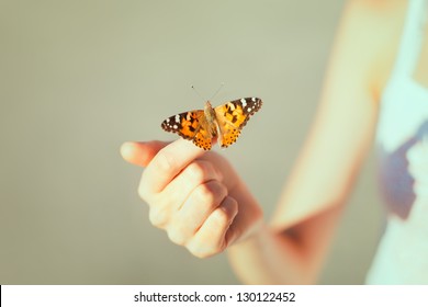 Beautiful butterfly sitting on the girl hand